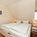 Schlafzimmer mit Doppelbett, Nachttisch und Fenster.
