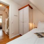 Schlafzimmer mit Dachschräge, weißem Schrank und Bett. Flur mit Treppe und weiterem Schlafzimmer.