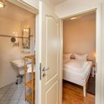 Zimmer mit Bett und angrenzender Badewanne mit Waschbecken.