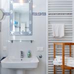 Badezimmer mit Spiegel, Waschbecken und Handtuchhalter.