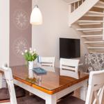 Esszimmer mit Tisch, Stühlen, Fernseher und Treppe.
