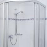 Dusche mit Duschbrause und Glaswand. Fliesen mit Meeresmotiv.