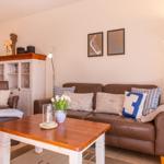 Wohnzimmer mit braunem Sofa, Holztisch und dekorativen Kissen.