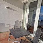 Terrasse mit Tisch und zwei Stühlen, Blick auf Wasser.