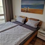 Schlafzimmer mit Doppelbett, zwei Nachttischen und Blick auf den Strand.