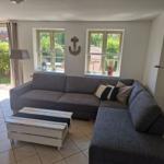 Wohnzimmer mit grauem Sofa, weißen Fenstern und Terrassentür.