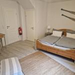 Schlafzimmer mit Doppelbett, Schreibtisch und Wanddekoration.