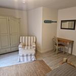 Schlafzimmer mit Kleiderschrank, Sessel, Schreibtisch und Spiegel an der Wand.