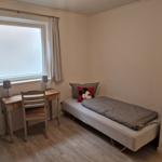 Ein Schlafzimmer mit einem Bett, einem Schreibtisch und einem Fenster.