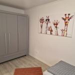 Schlafzimmer mit Kleiderschrank und Giraffenbild an der Wand.