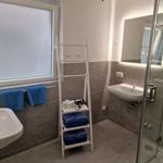 Badezimmer mit Dusche, Waschbecken und blauen Handtüchern.