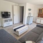 Wohnzimmer mit Sofa, Couchtisch, Fernseher und Schränken.