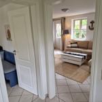 Wohnzimmer mit Sofa, Couchtisch und Fenster. Tür führt in Schlafzimmer mit blauer Couch.