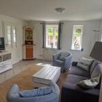 Wohnzimmer mit Sofa, Sessel, Couchtisch und Fernseher.