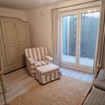 Zimmer mit Schrank, Sessel, Tisch und Fenster zum Balkon.