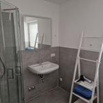 Badezimmer mit Dusche, Waschbecken und Fenster