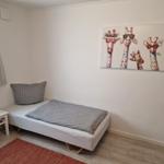 Ein Schlafzimmer mit Bett, Nachttisch und Wandbild mit Giraffen.