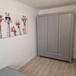 Schlafzimmer mit Kleiderschrank und Giraffenbild an der Wand.