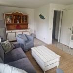 Wohnzimmer mit Sofa, Sessel, Couchtisch und TV.