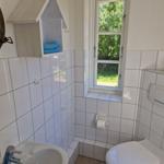 Badezimmer mit Toilette, Waschbecken und Fenster mit Blick auf Garten