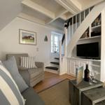 Wohnzimmer mit Sofa, Fernseher und Treppe zur oberen Etage.