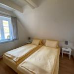 Zimmer mit zwei Betten, Fenster und Nachttischen.