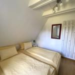 Schlafzimmer mit Doppelbett, Spiegel und Heizkörper an der Wand.