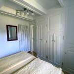 Schlafzimmer mit Bett, weißen Schränken und Spiegel an der Wand.