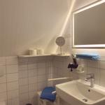 Badezimmer mit Waschbecken, Spiegel und Handtuchhalter.