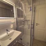 Badezimmer mit Dusche, Waschbecken und Spiegel.