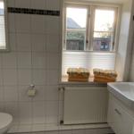 Badezimmer mit Toilette, Waschbecken und Fenster mit Handtüchern.