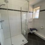 Badezimmer mit Dusche, Toilette und Fenster.