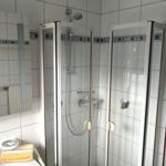 Badezimmer mit Duschkabine, Spiegel und Waschbecken.