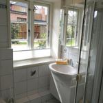 Badezimmer mit Waschbecken, Dusche und Fenster zur Außenseite.