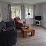 Wohnzimmer mit Sofa, Sessel, Tisch und Fernseher.