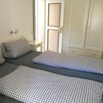 Zwei Betten mit karierten Bettwäsche, Schrank und Stuhl im Schlafzimmer.