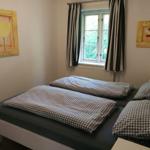 Schlafzimmer mit Doppelbett, Fenster und Wandbildern.