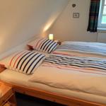 Zimmer mit Doppelbett, Nachttisch und Fenster. Bett mit Streifenbezug.