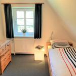 Ein Schlafzimmer mit Bett, Schrank und Fenster. Auf dem Fensterbrett steht eine Pflanze.