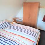 Schlafzimmer mit Bett, Kleiderschrank und Jacke an Wandhaken.