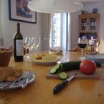 Holztisch mit Frühstück, Wein, Gemüse und Kerze.