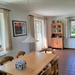 Esszimmer mit Holztisch, Stühlen und Terrassentür. Terrakottafußboden und Holzschrank.
