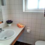 Badezimmer mit Waschbecken, Spiegel, Toilette und Fenster.