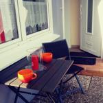 Terrasse mit Tisch, Stühlen und orangefarbenen Tassen.