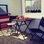 Außenbereich mit Tisch, Stühlen und gelbem Sonnenschirm.