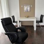 Black leather chair and table with chairs in room.