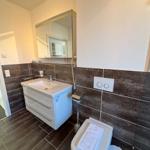 Bathroom with sink, mirror, and toilet. Tiled wall and floor.