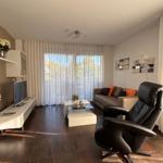 Living room with sofa, leather chair, TV, and window with curtains.