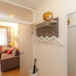 Eingangsbereich mit Garderobe, Spiegel und Sicht auf Wohnzimmer mit Sofa.
