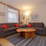 Wohnzimmer mit zwei grauen Sofas, Holztisch und Blumentopf.